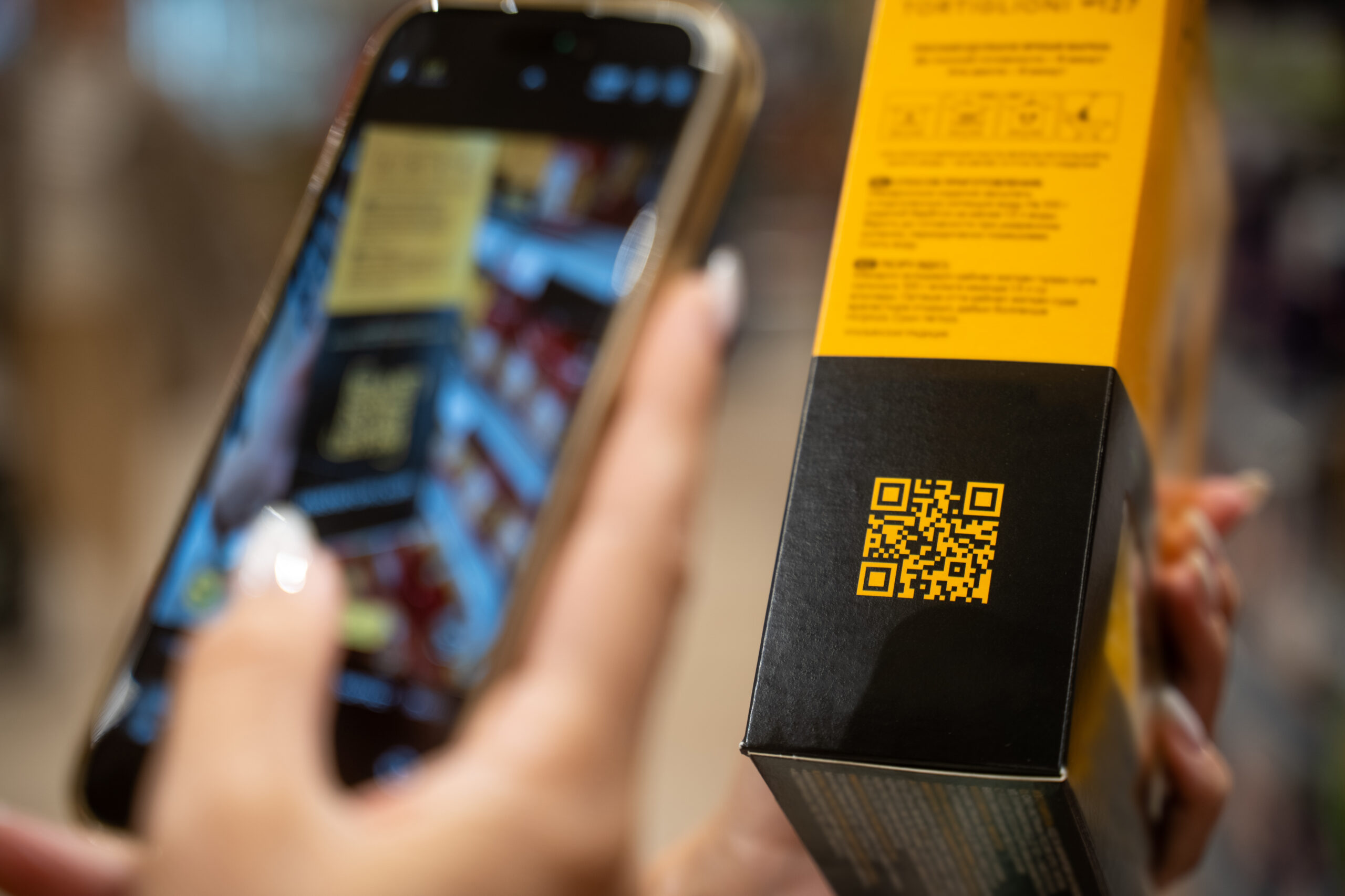 Kupac skenira QR kod na kutiji (ambalaži) prehrambenog proizvoda.
